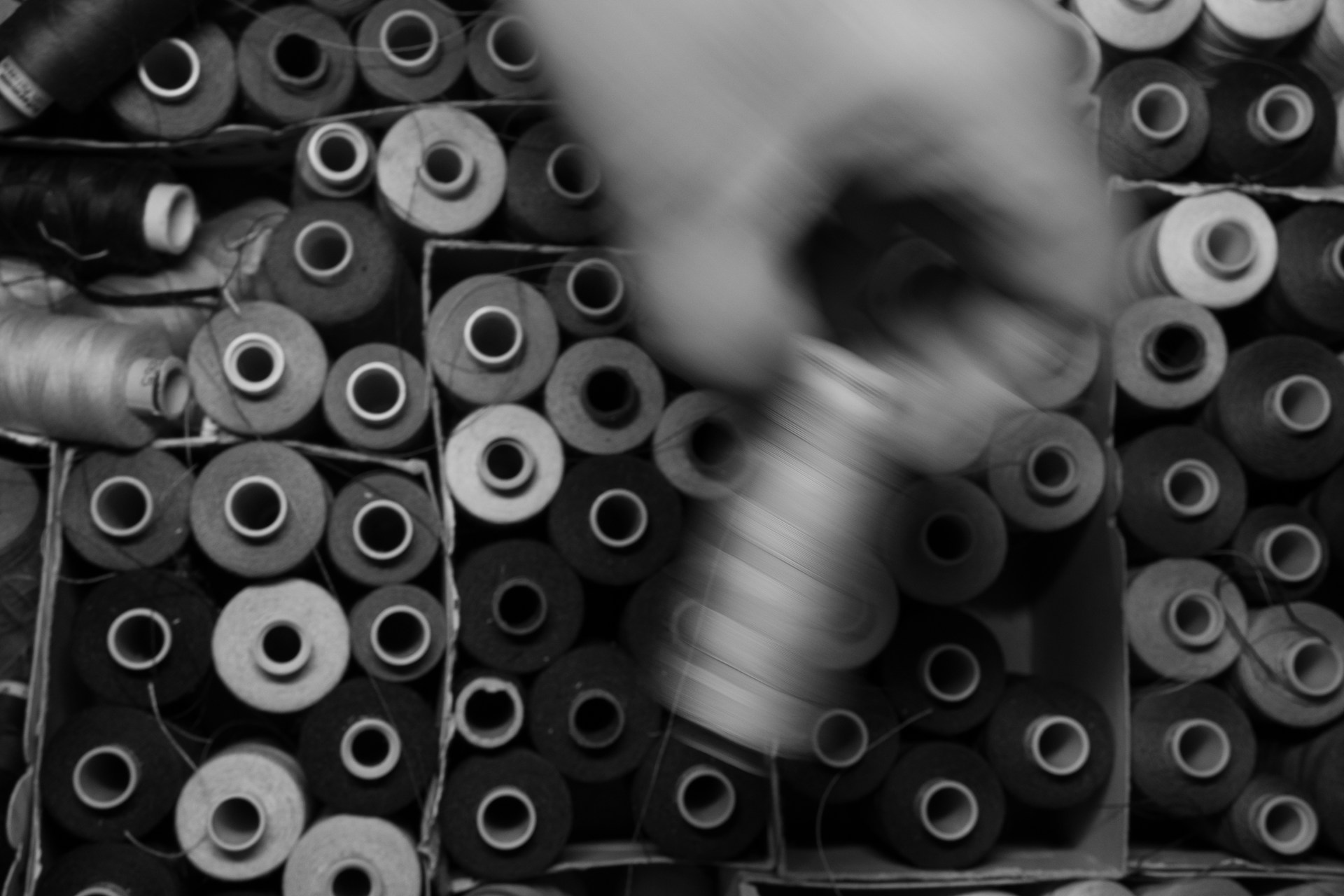 A person is sprinkling a spool of thread with a machine