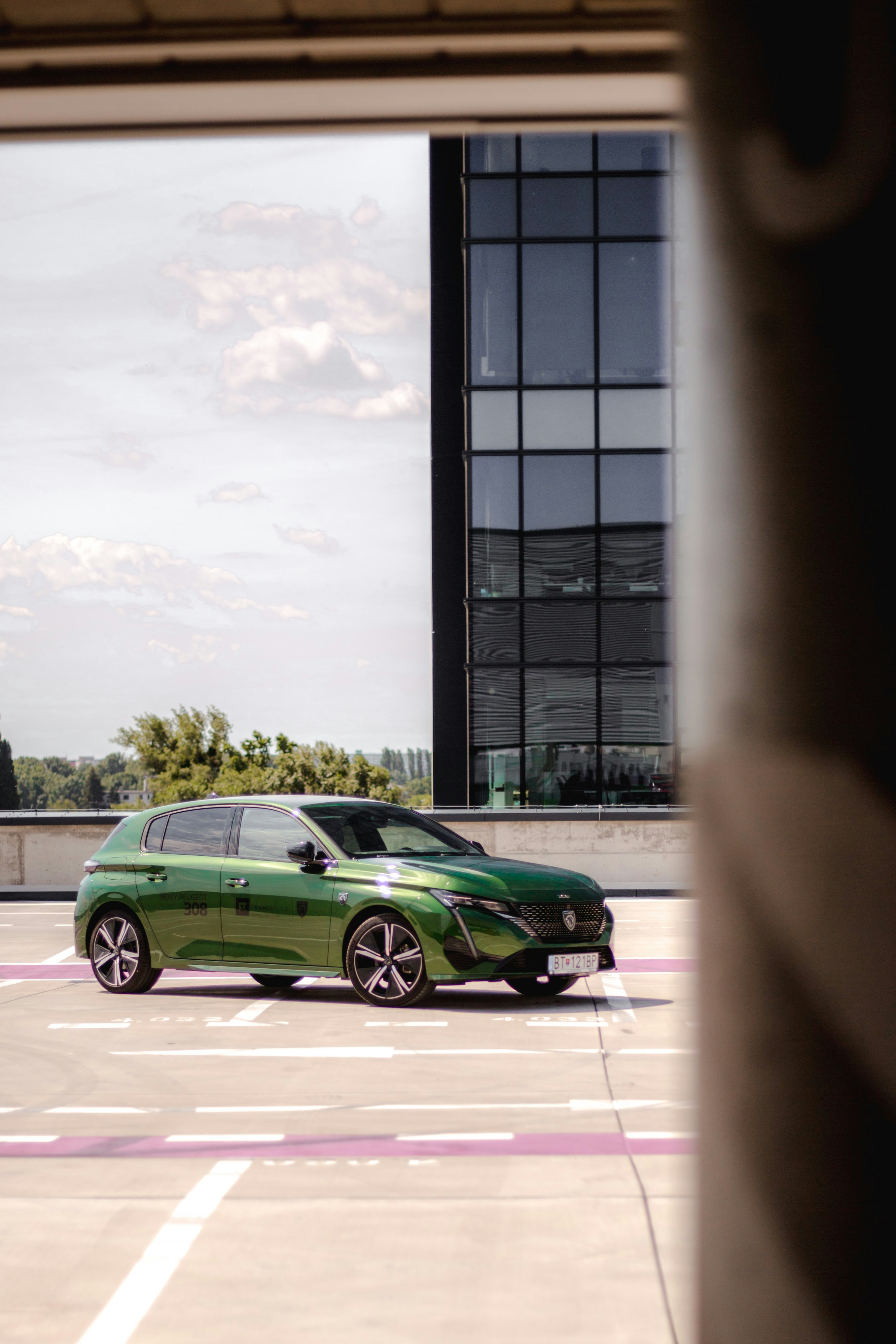 A green car is parked in a parking lot