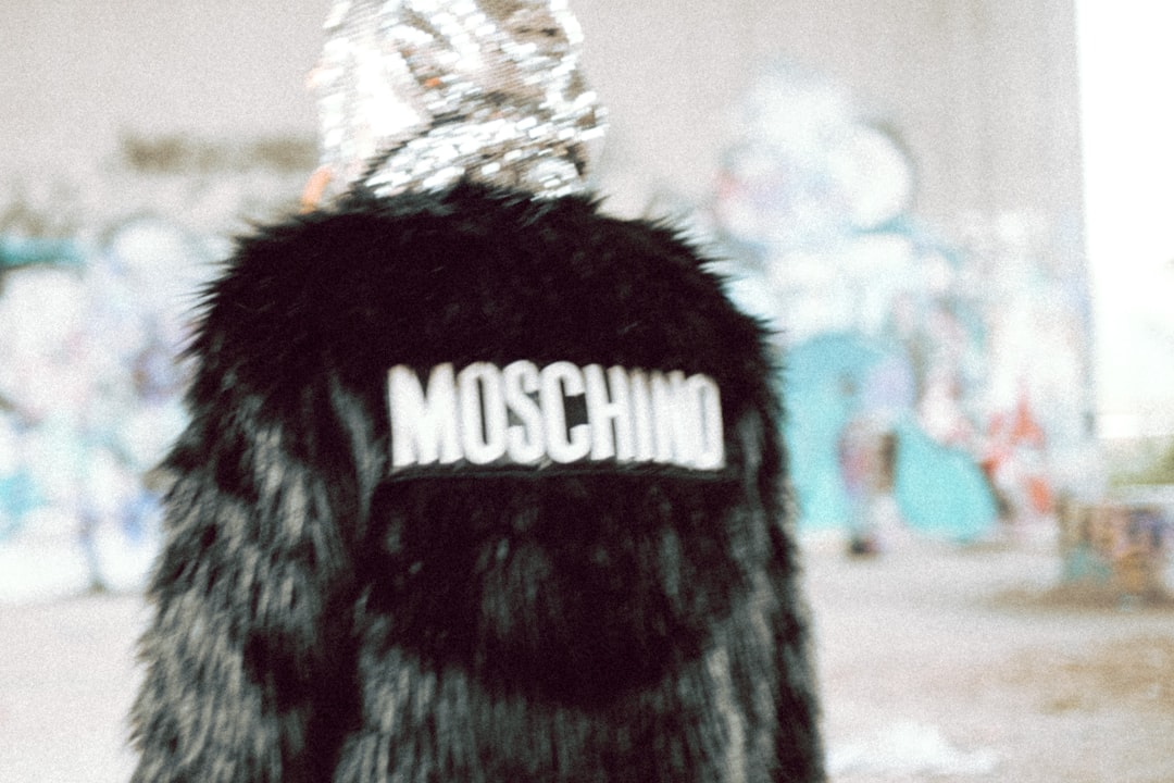A woman in a black fur coat with the word moschino on it, for Moschino.