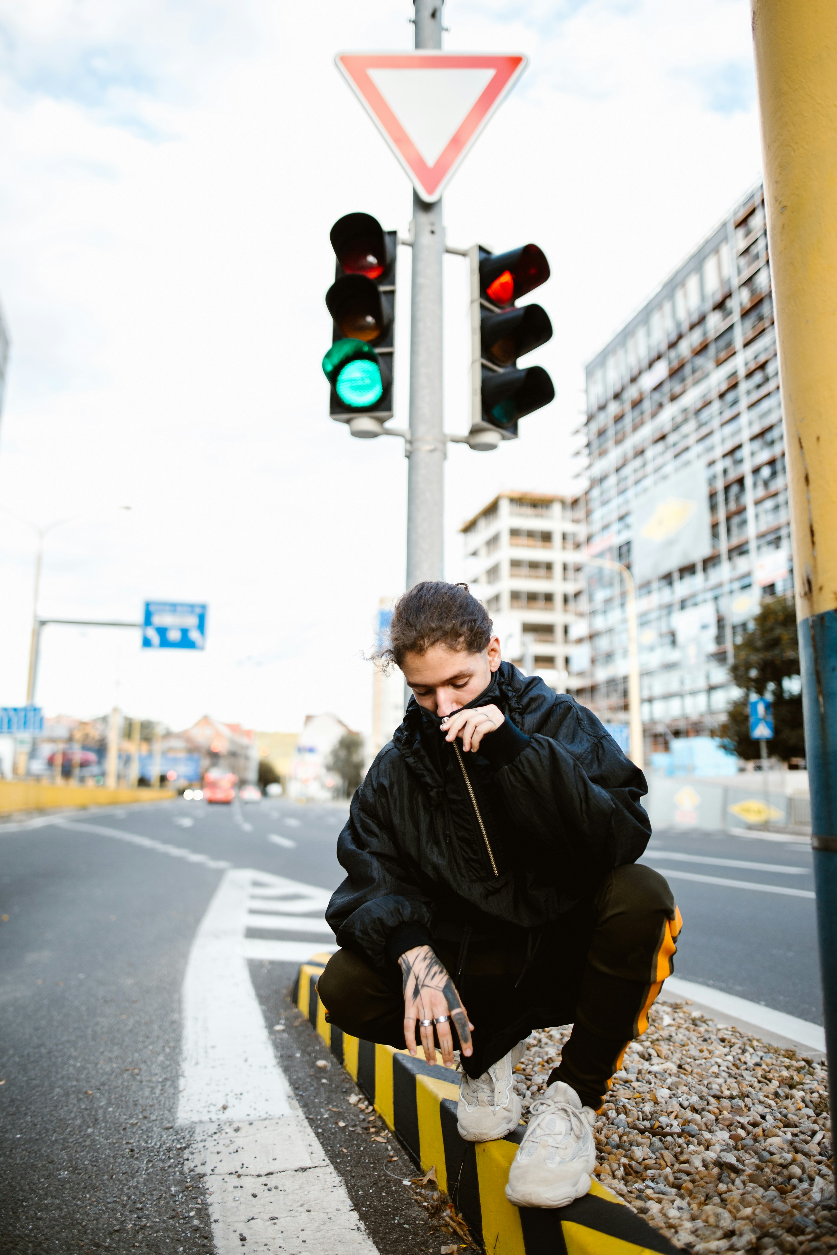 A man sitting on a curb next to a traffic light