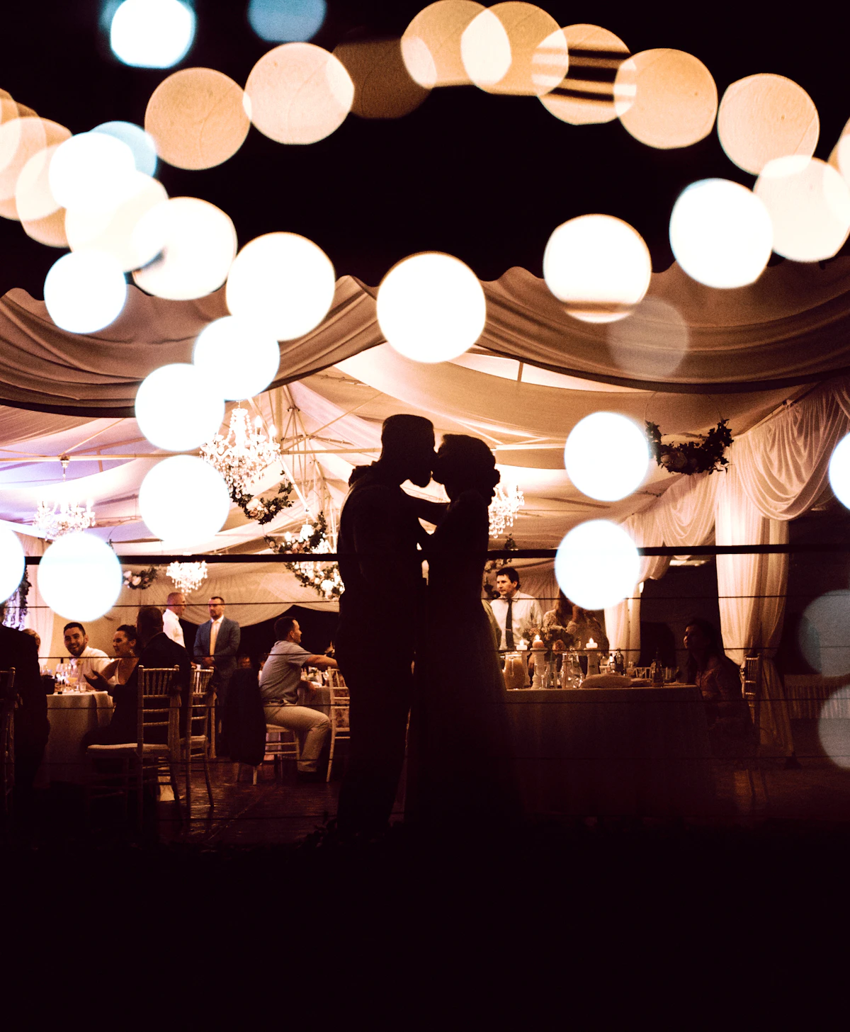 Couple under string lights at an evening wedding