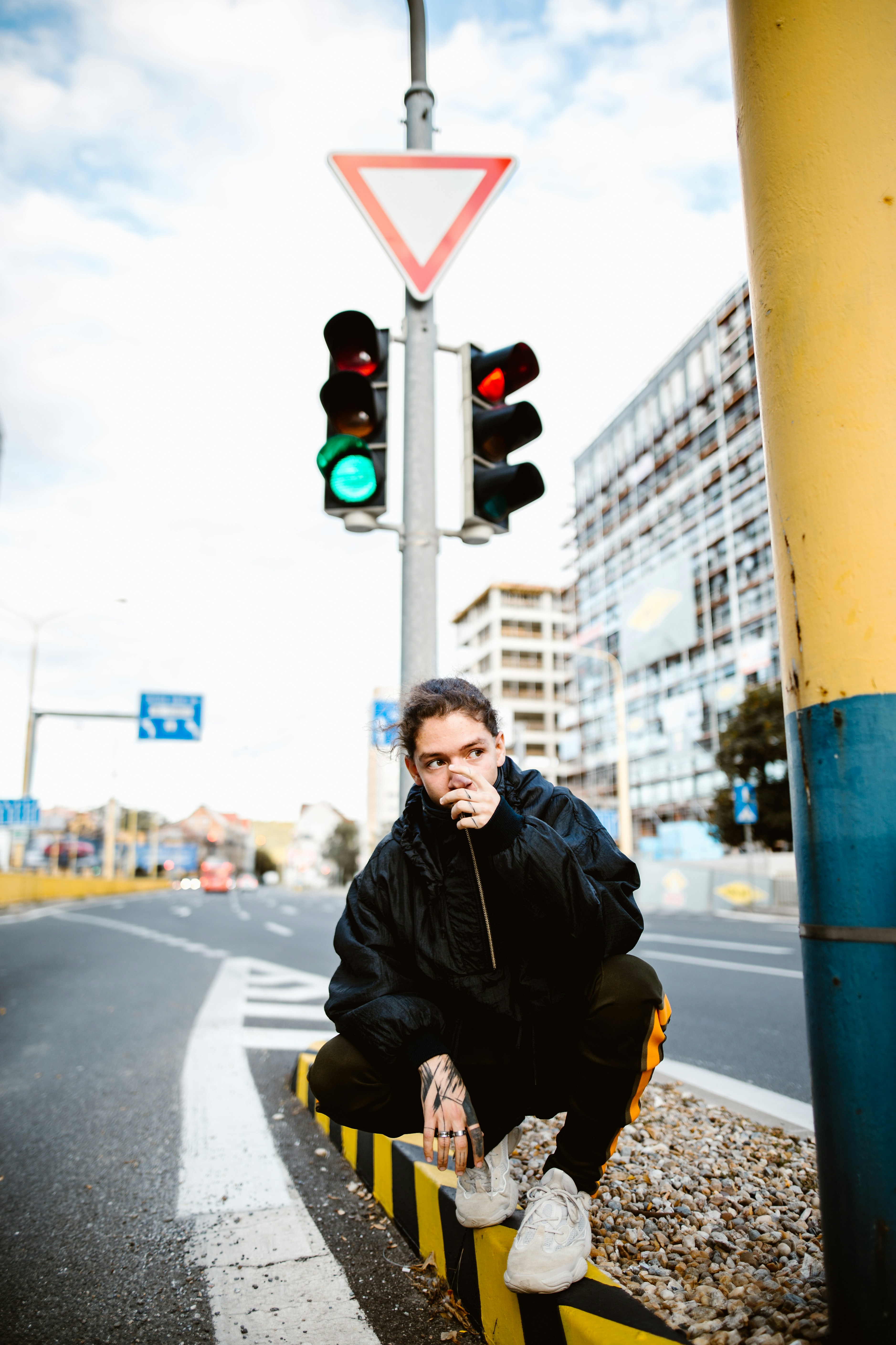 A man sitting on a yellow curb next to a traffic light