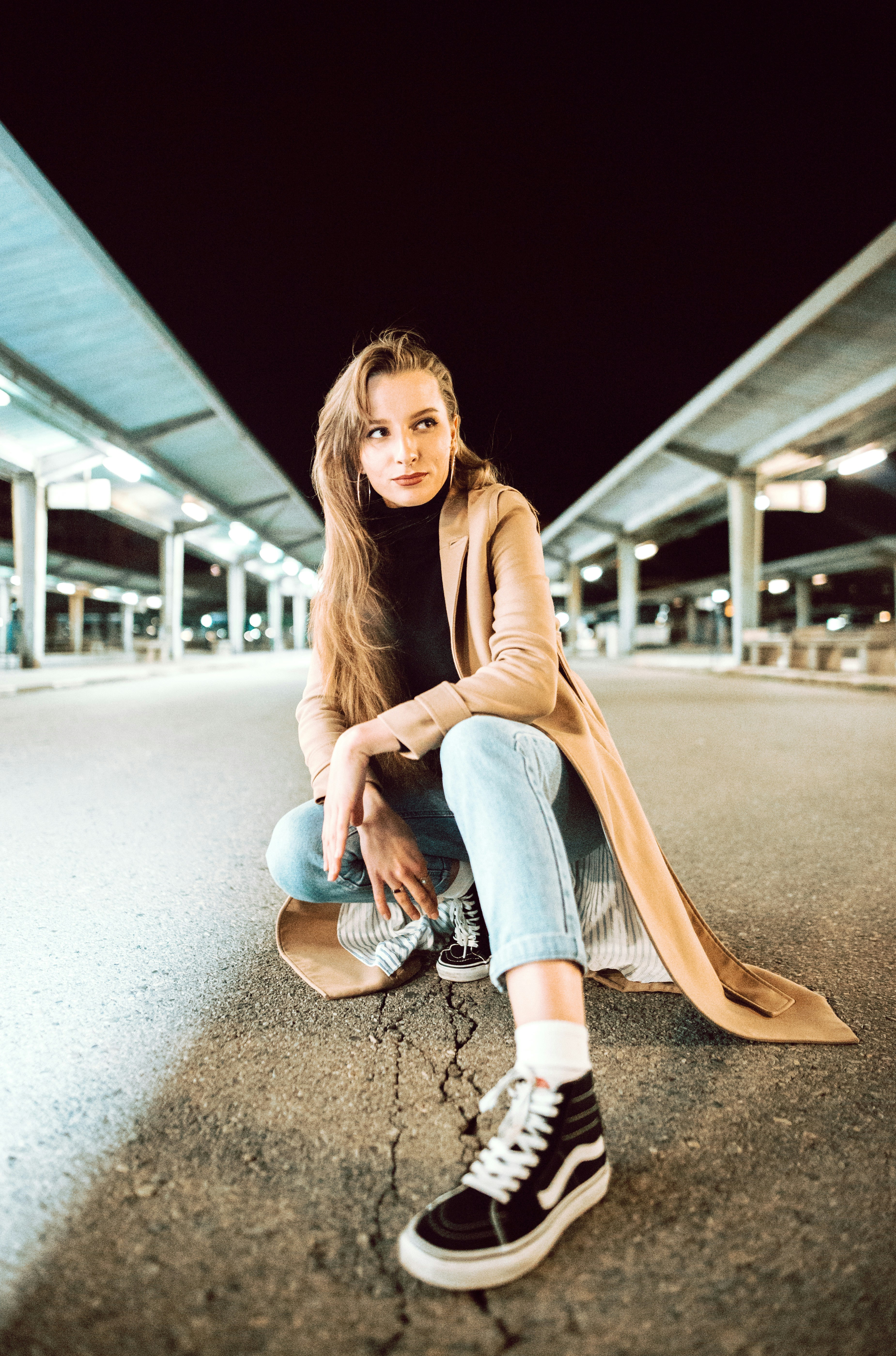 A woman sitting on a skateboard in a parking lot