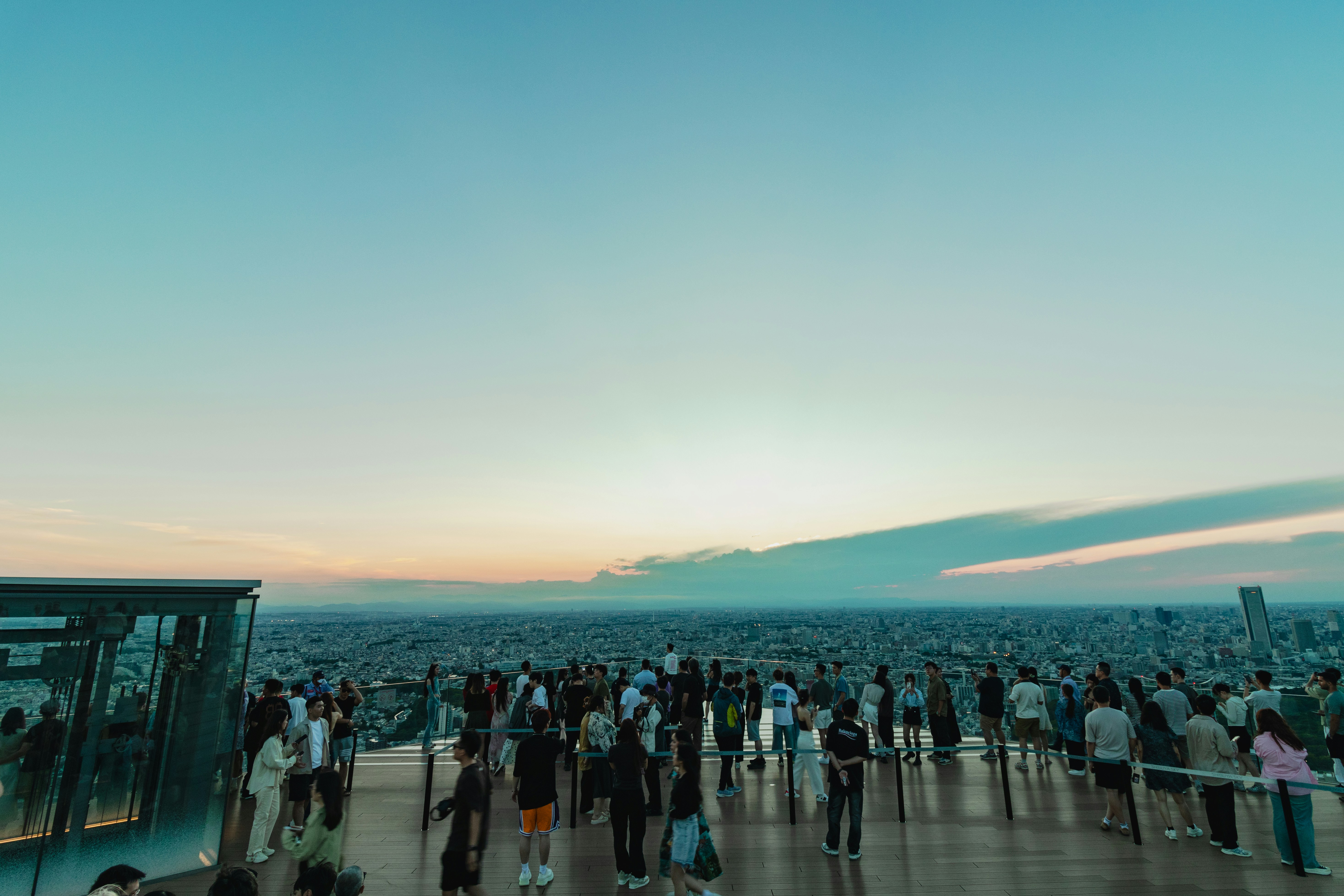 Crowd of people looking towards a sunrise from an urban observation deck