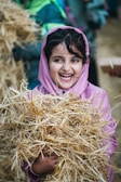 A young girl holding a pile of hay