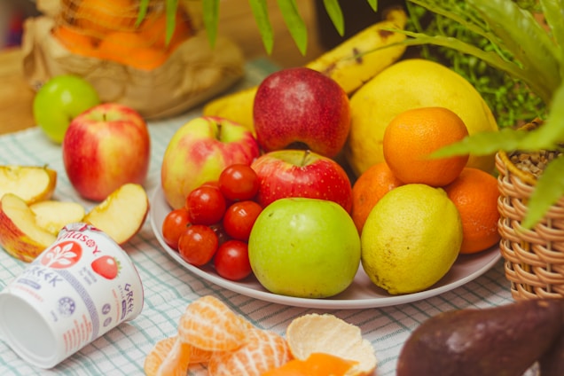 A table topped with a plate of fruit and a cup of milk