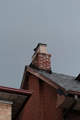A red brick building with a black roof and a chimney