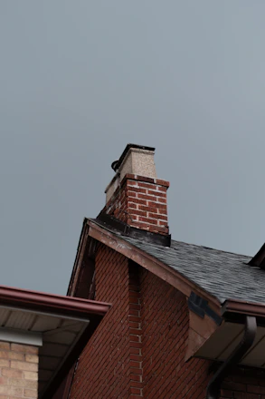 A red brick building with a black roof and a chimney