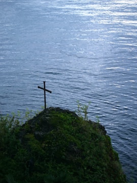 A cross on a hill overlooking a body of water