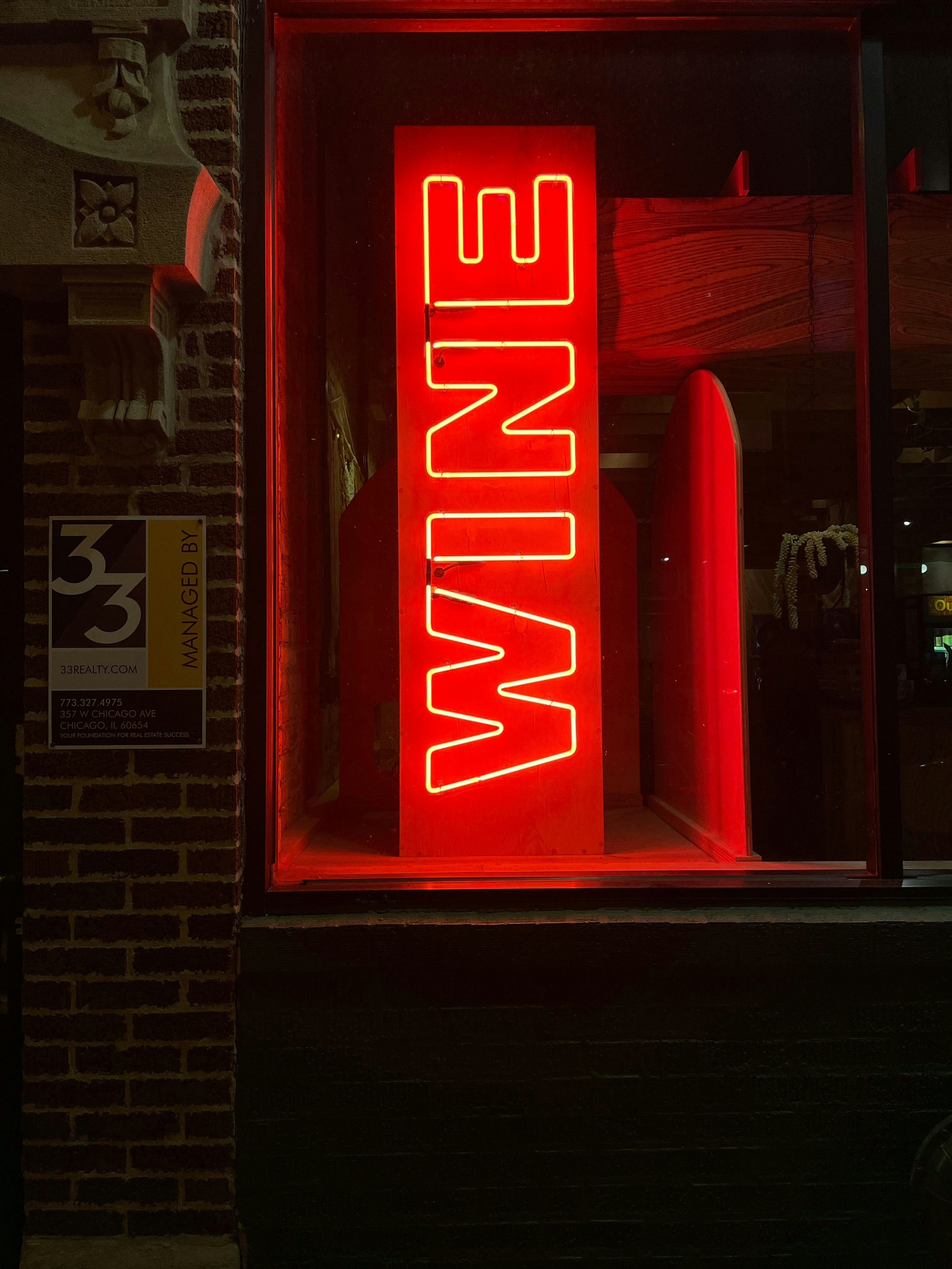 A red neon sign that is on the side of a building photo – Free Light ...