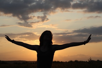 A person standing in a field with their arms outstretched