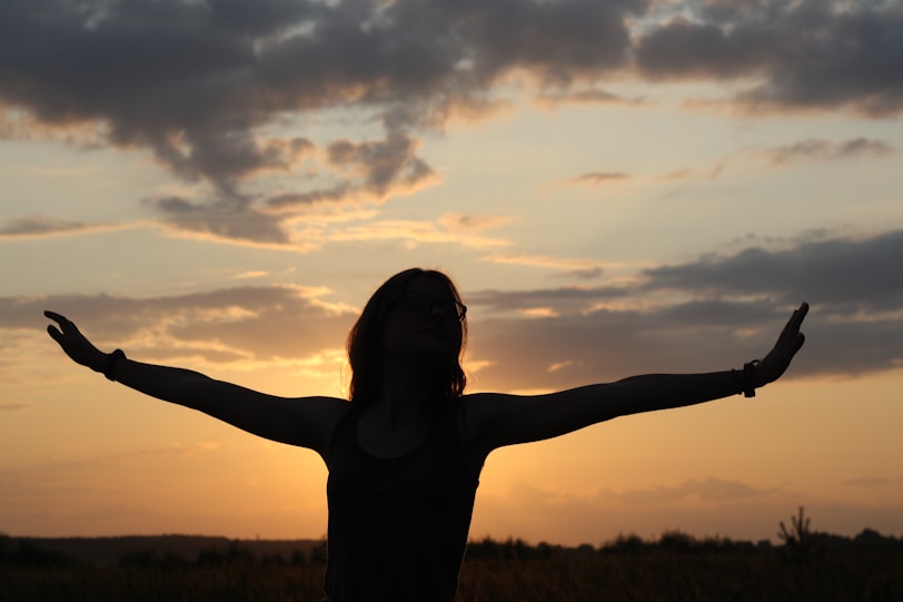 A person standing in a field with their arms outstretched