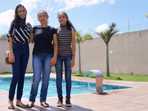 Three women standing in front of a swimming pool