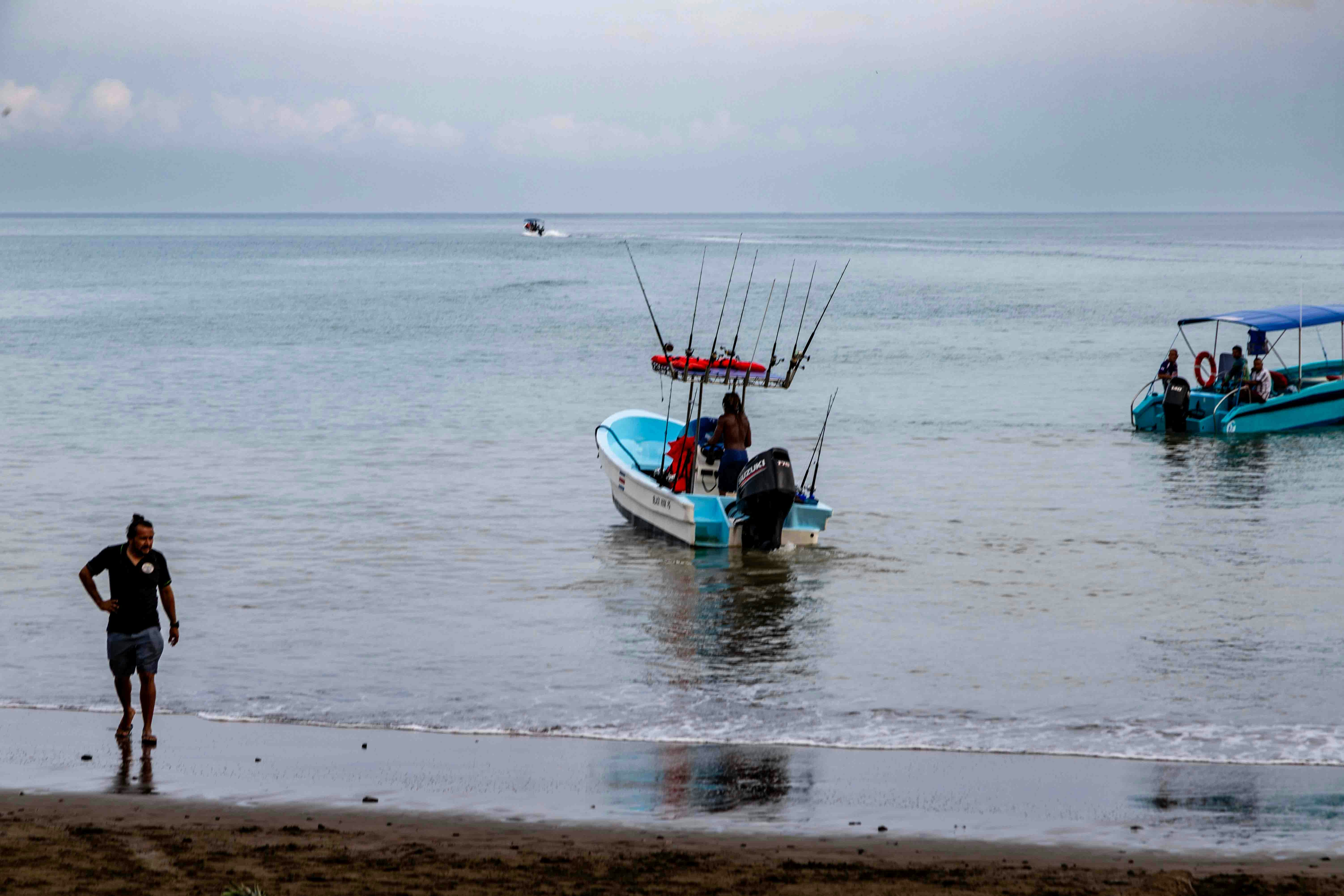 A group of people standing on top of a beach next to a boat