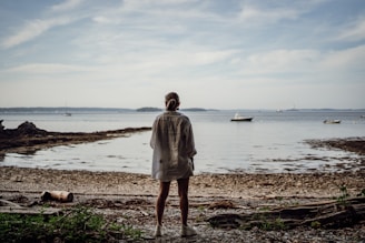 A person standing on a beach looking out at the water