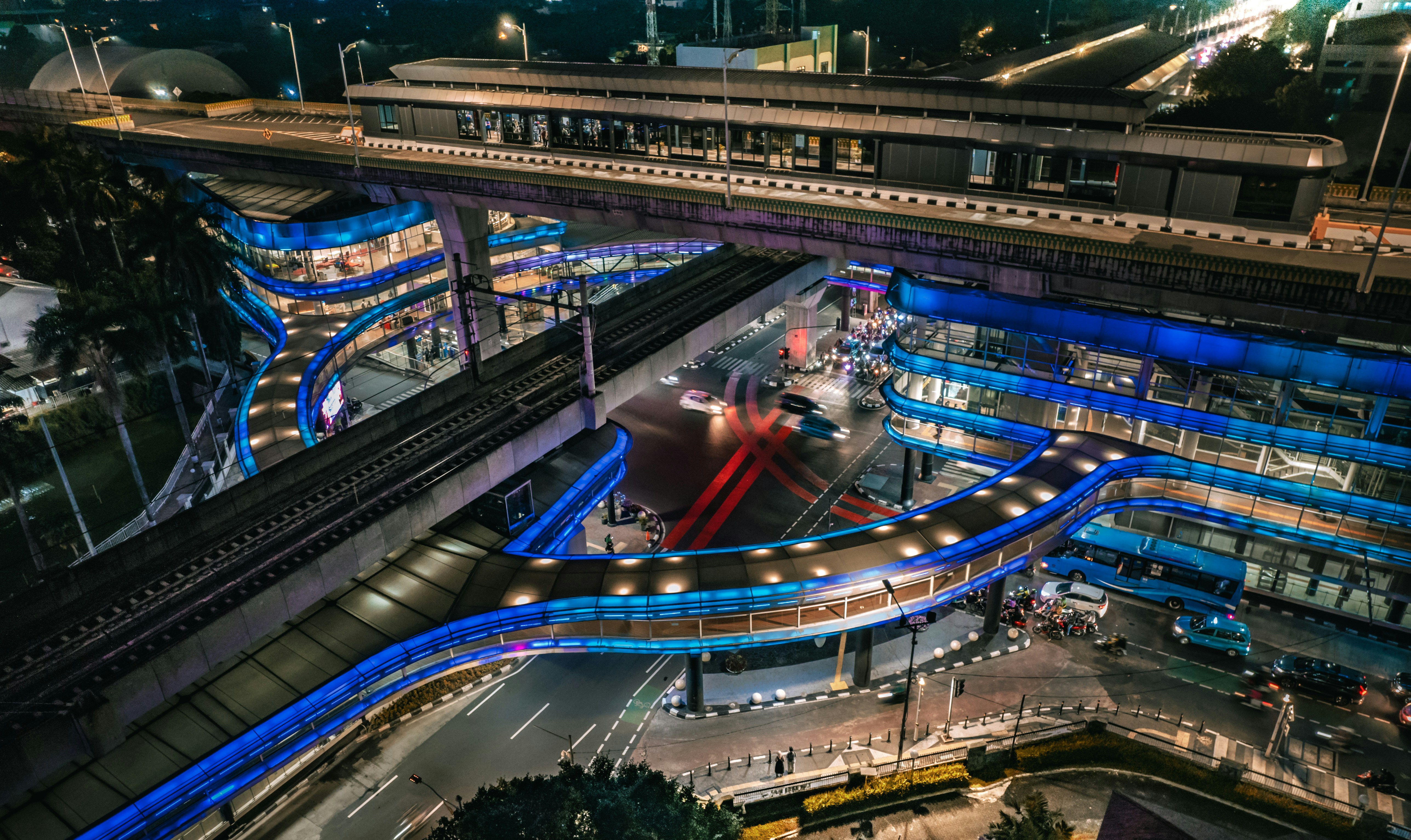 Modern transit station interior at night, dramatic concrete arches, deep shadows, ambient blue lighting from ceiling panels