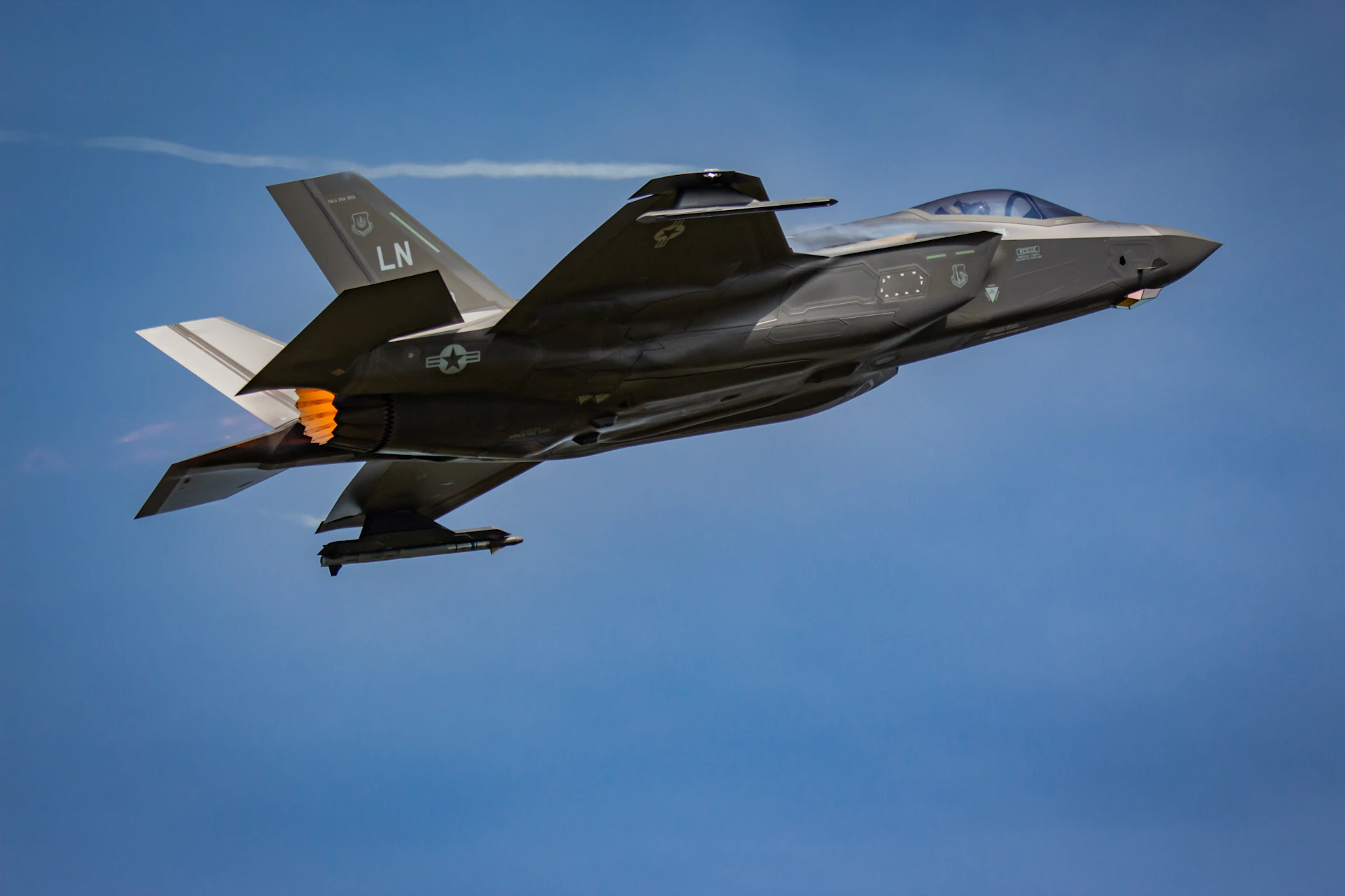 A fighter jet flying through a blue sky