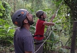 A man and a boy on a zip line in the jungle