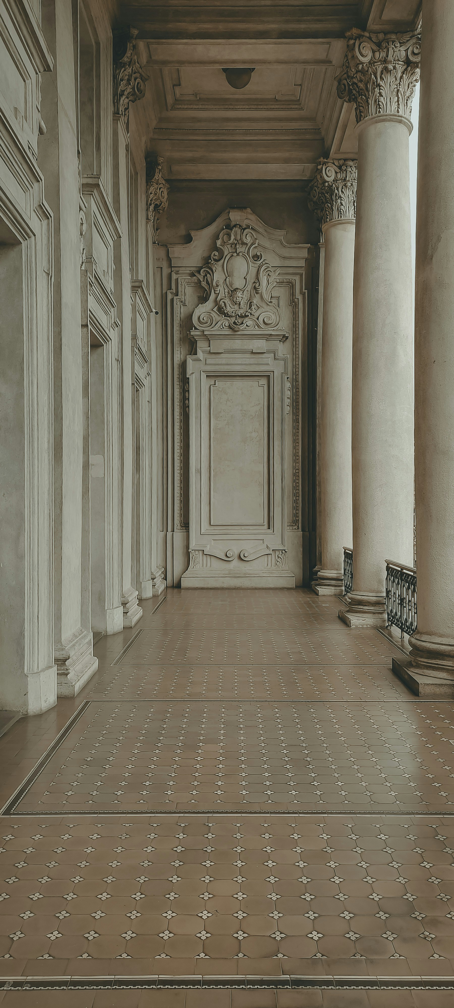 Um longo corredor com colunas e um banco