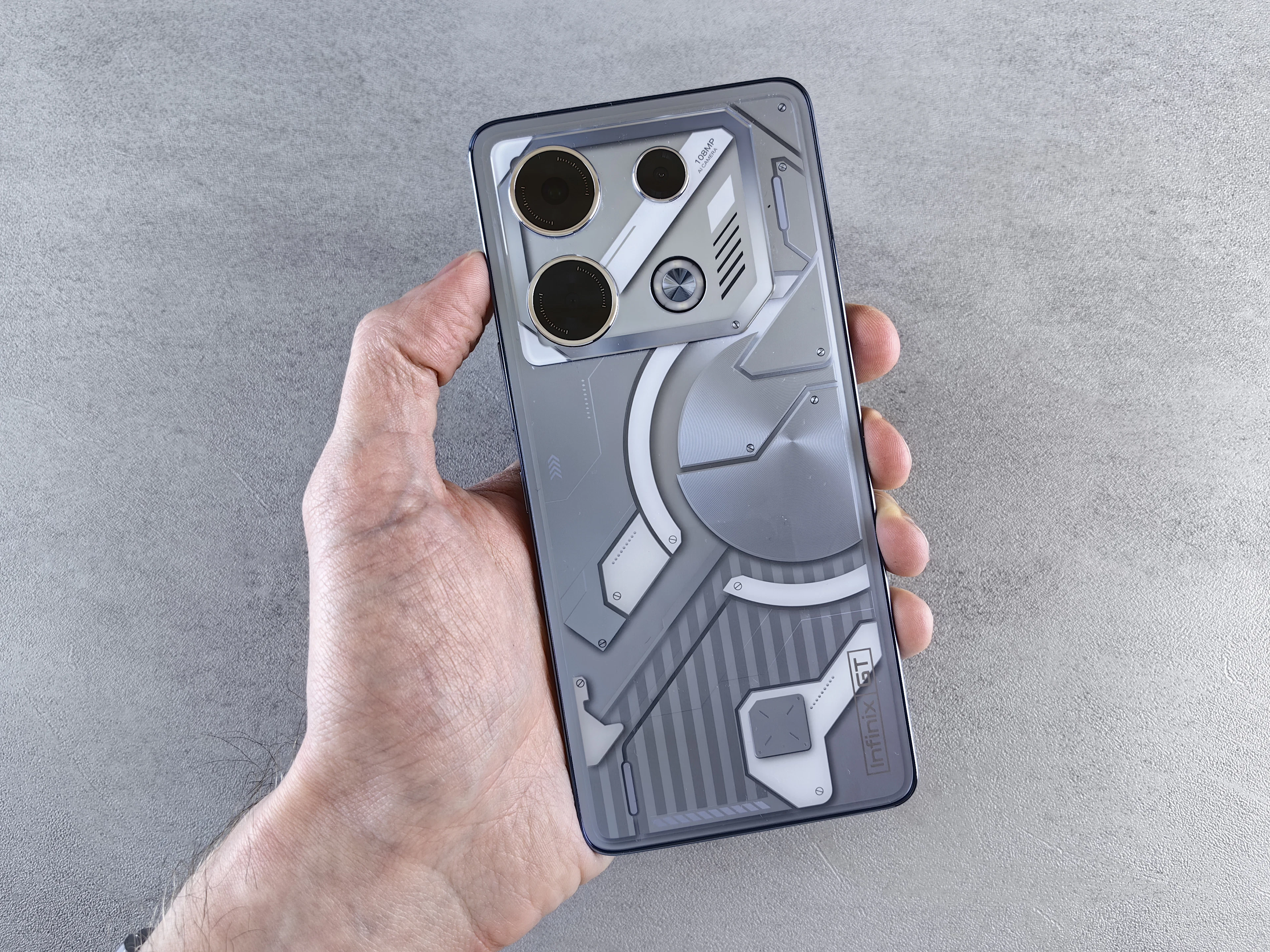 Hand holding a grey smartphone against a stone background