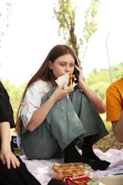 A group of people sitting on the ground eating food