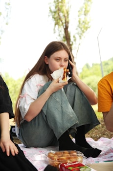 A group of people sitting on the ground eating food