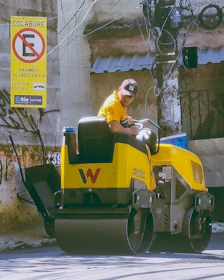A man driving a yellow machine down a street