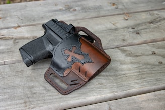 A leather holster with a gun on a wooden table