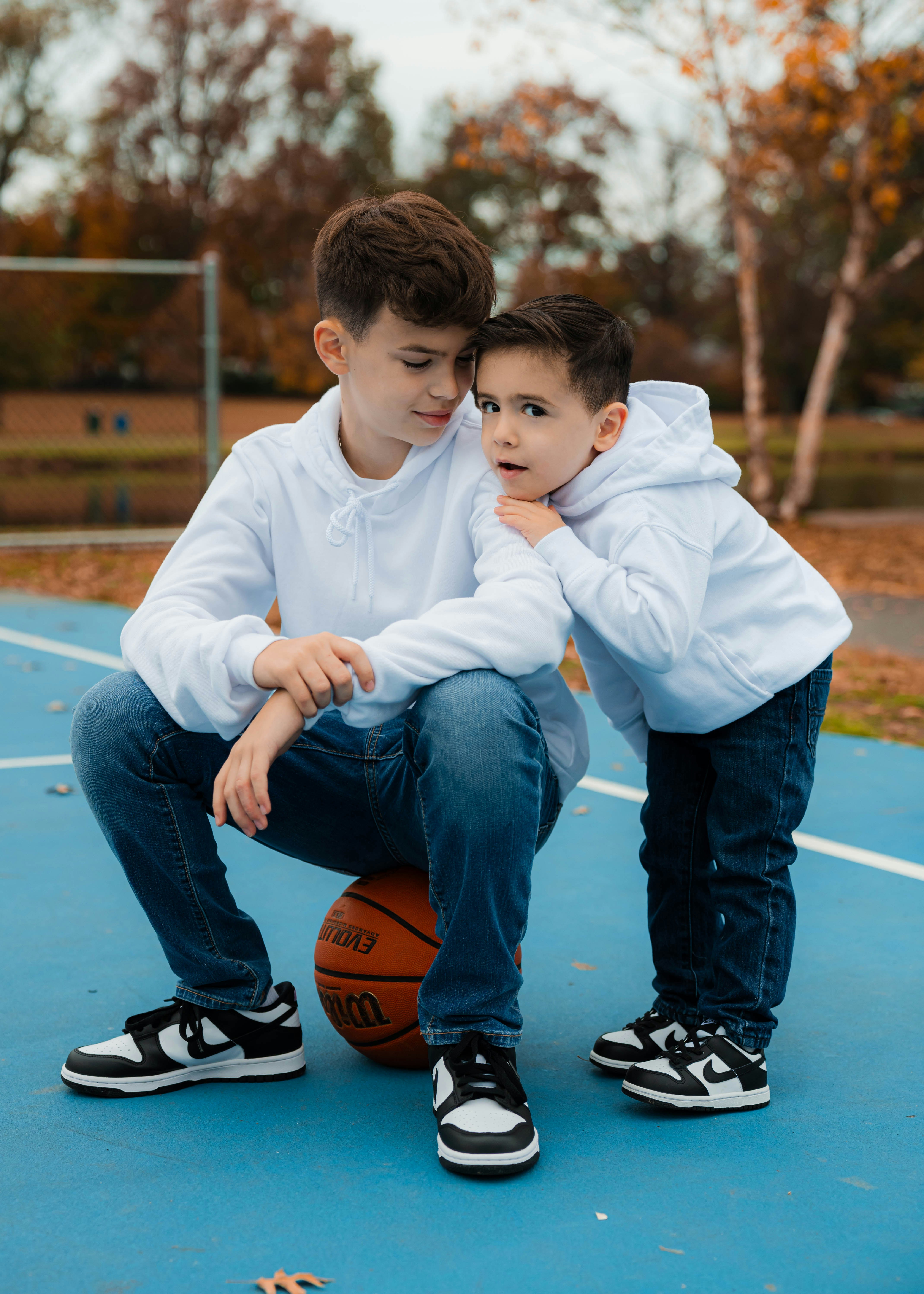 Two young boys sitting on a basketball court