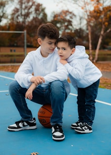 Two young boys sitting on a basketball court