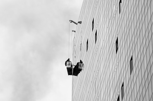 A black and white photo of a man hanging from a building