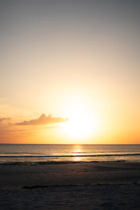 The sun is setting over the ocean on the beach