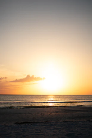 The sun is setting over the ocean on the beach