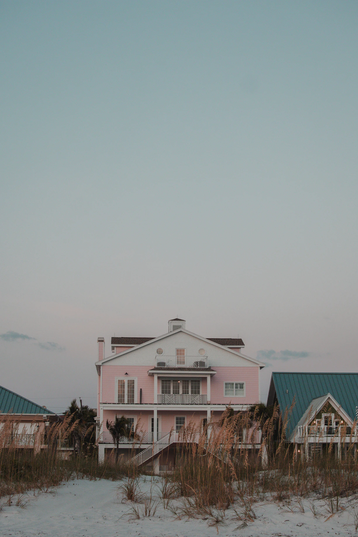A pink house sitting on top of a sandy beach