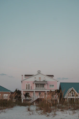 A pink house sitting on top of a sandy beach