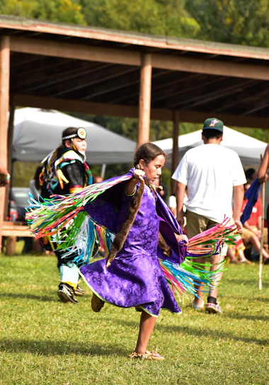 A young girl in a purple dress holding a colorful kite