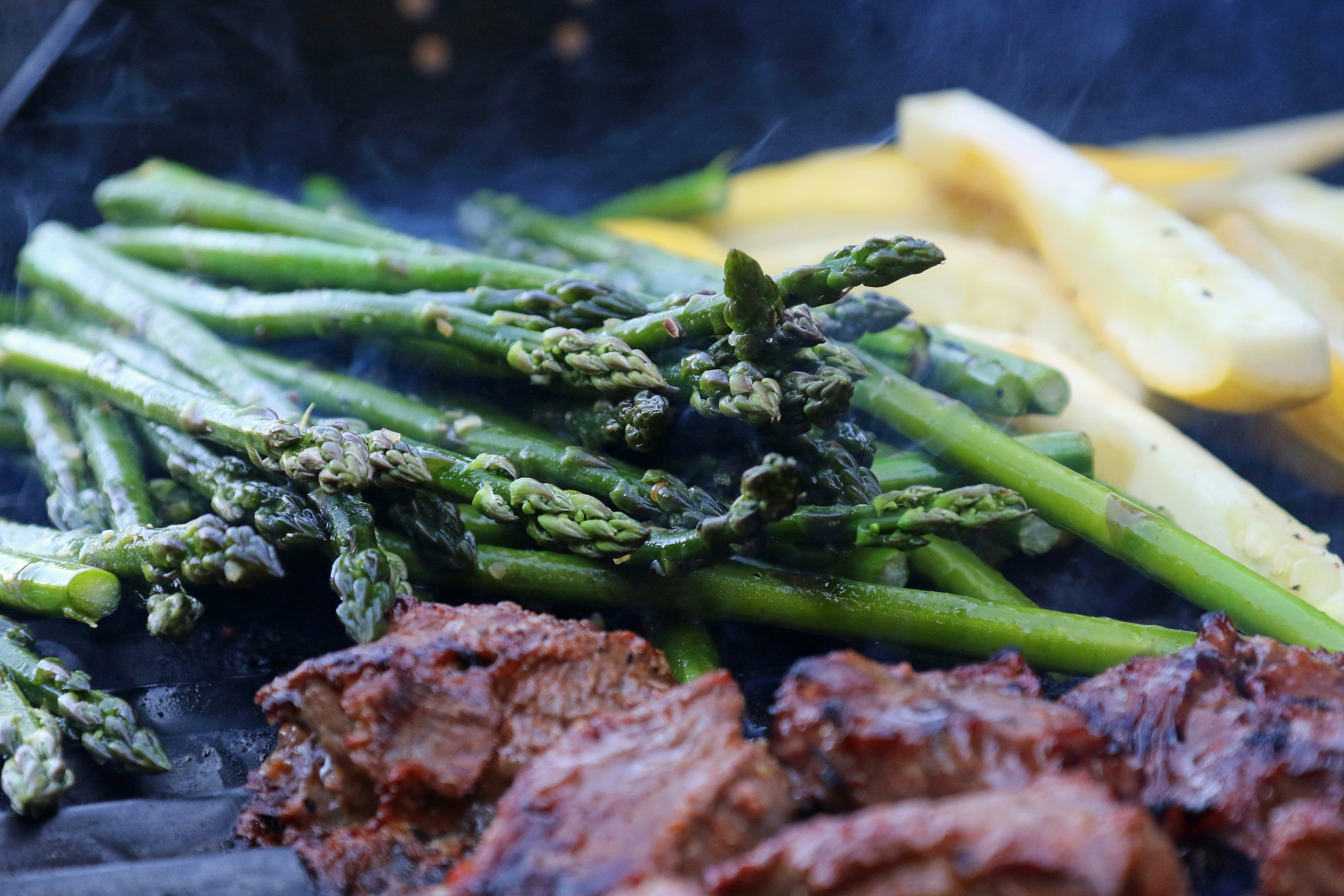 Steak and asparagus cooking on a grill