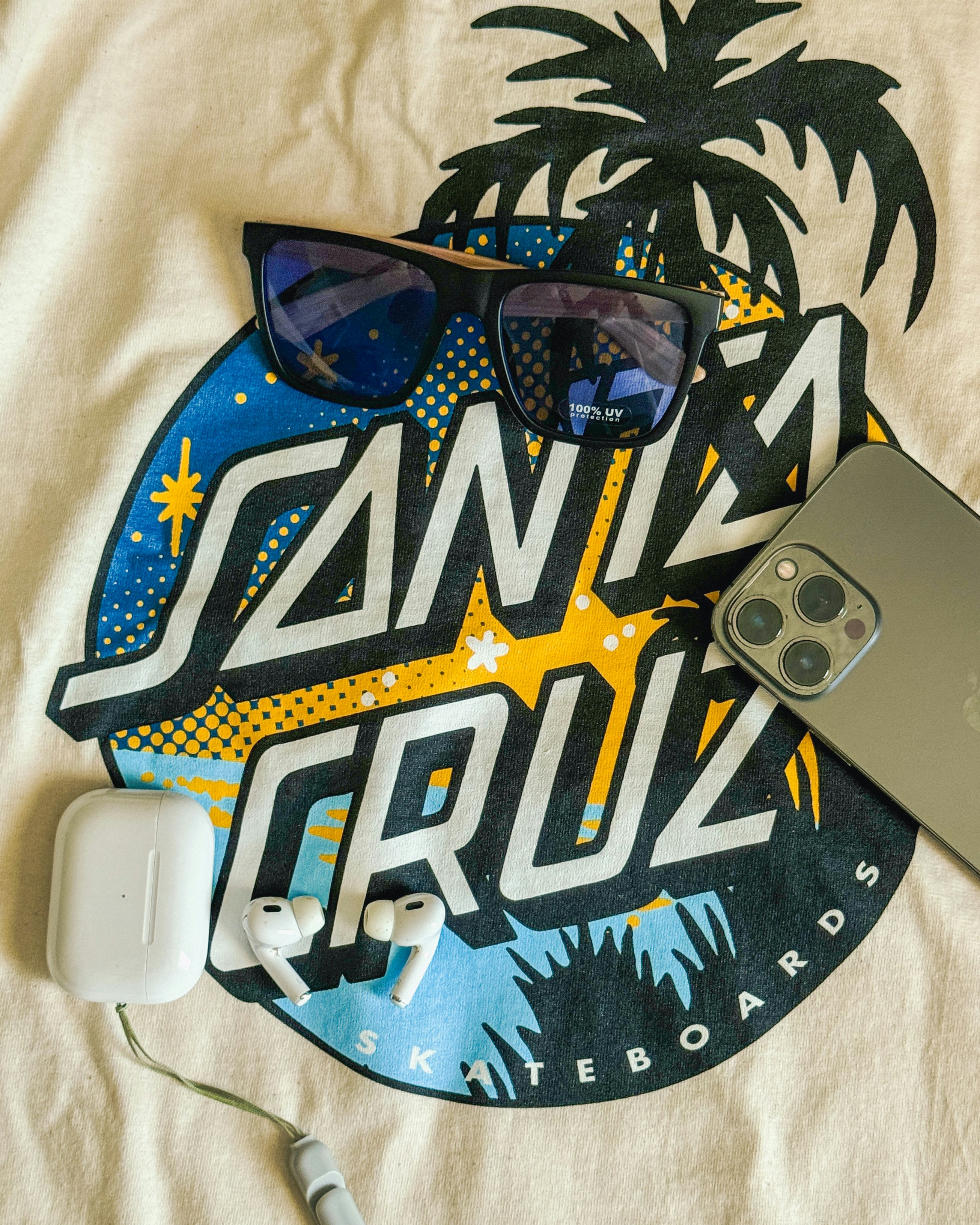 A cell phone, sunglasses, headphones, and a pair of headphones are