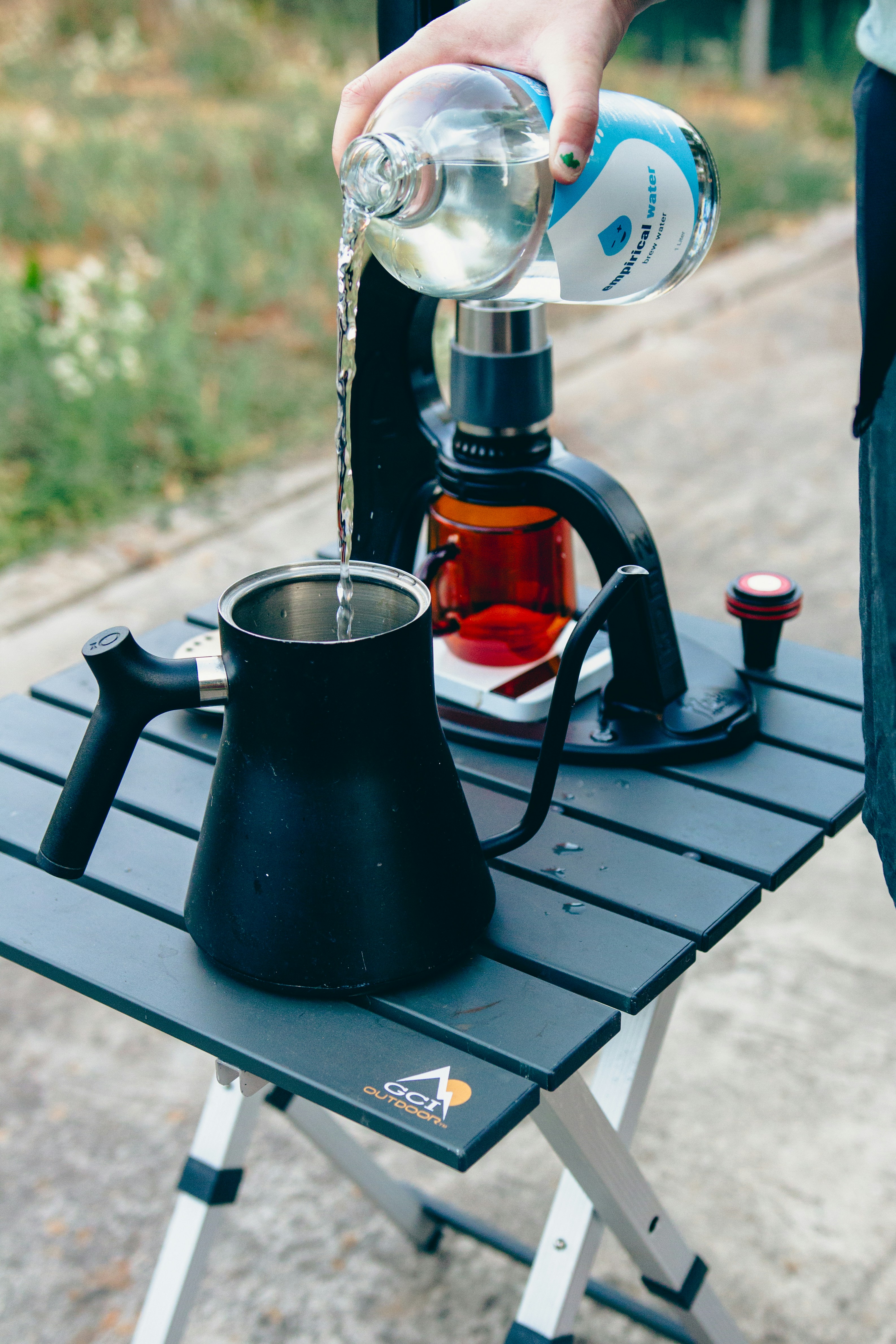 A person pours water into a coffee pot
