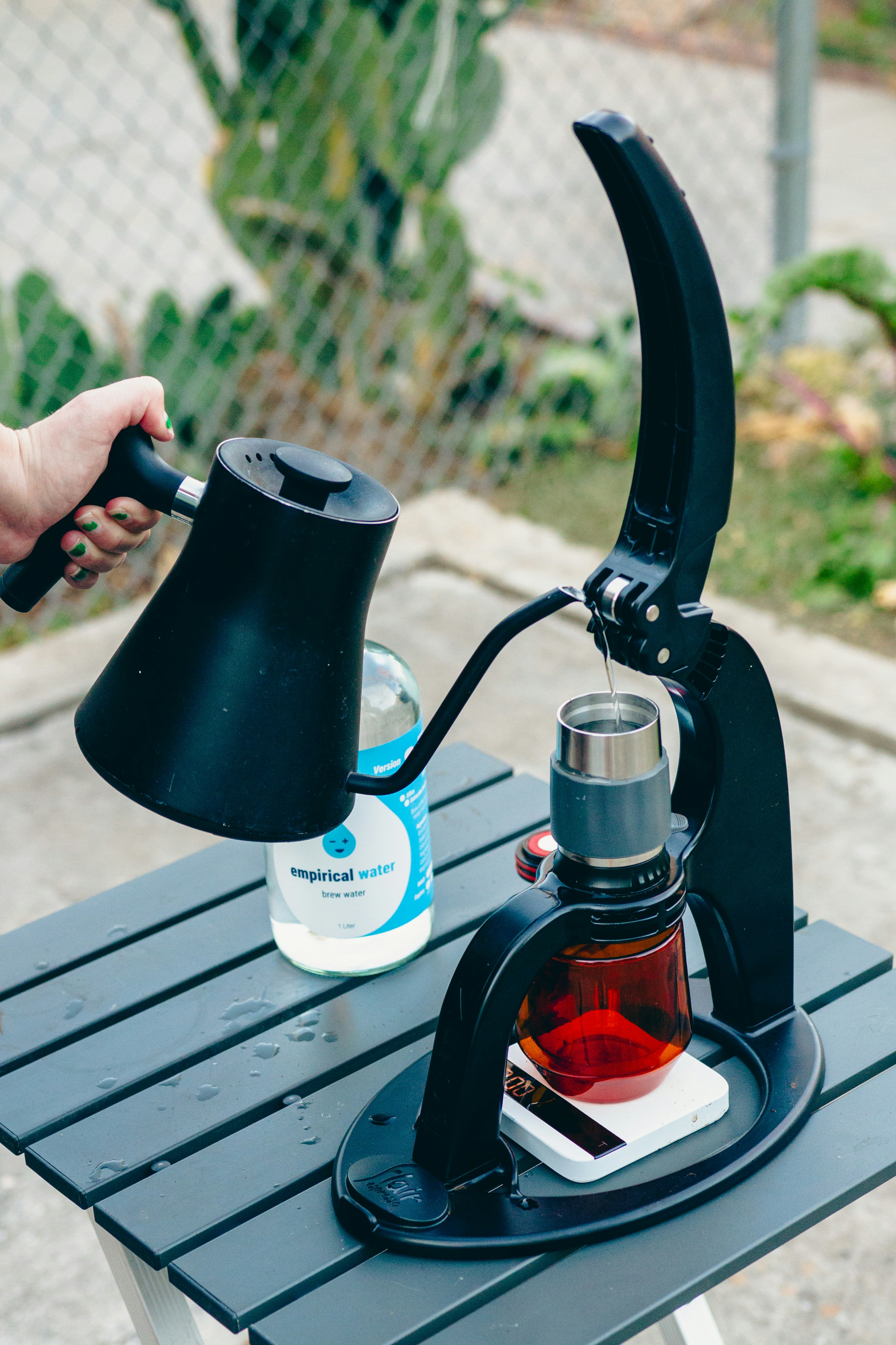 A person holding a coffee pot over a table