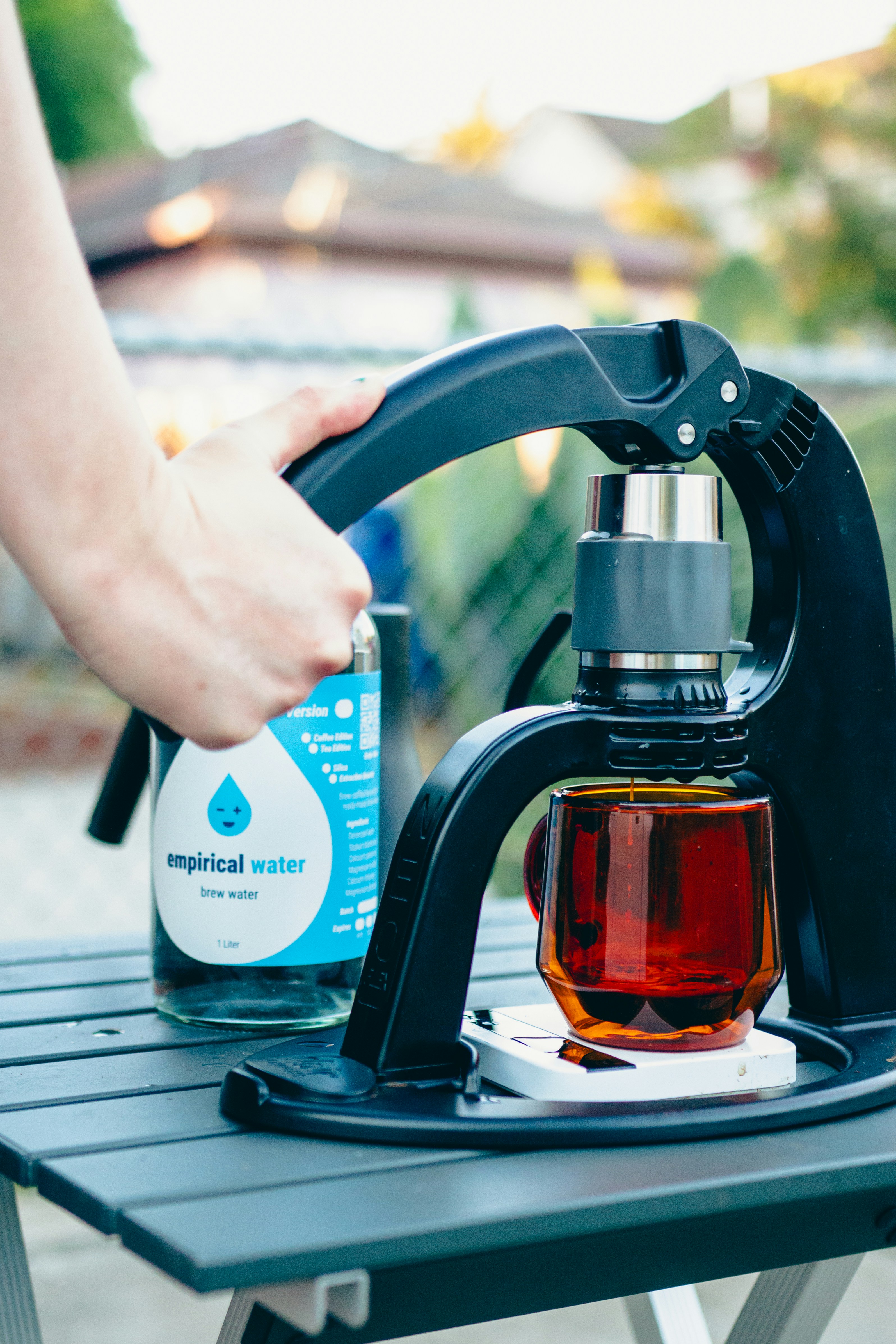 A person is holding a bottle of tea on a picnic table