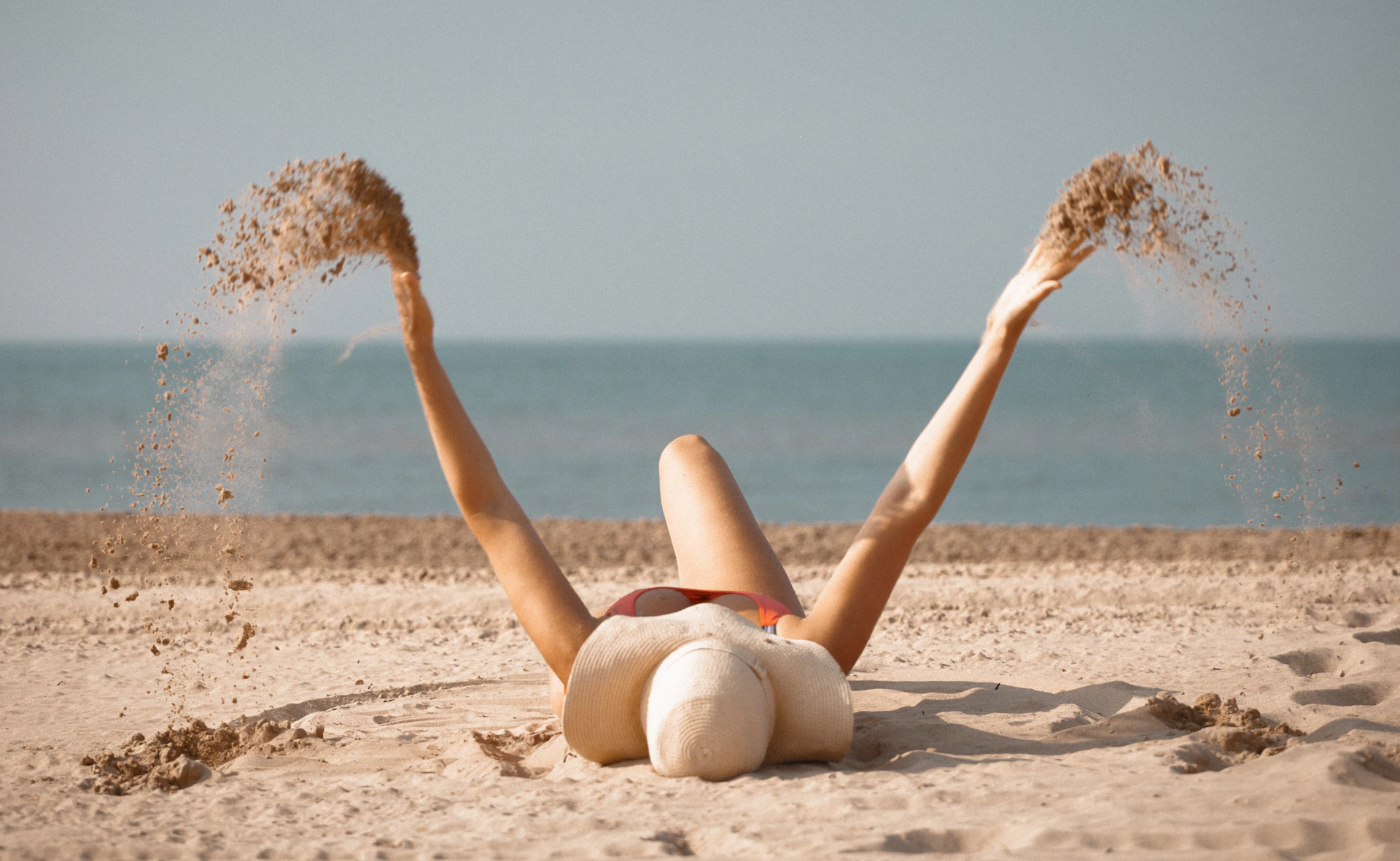 A woman laying in the sand on the beach