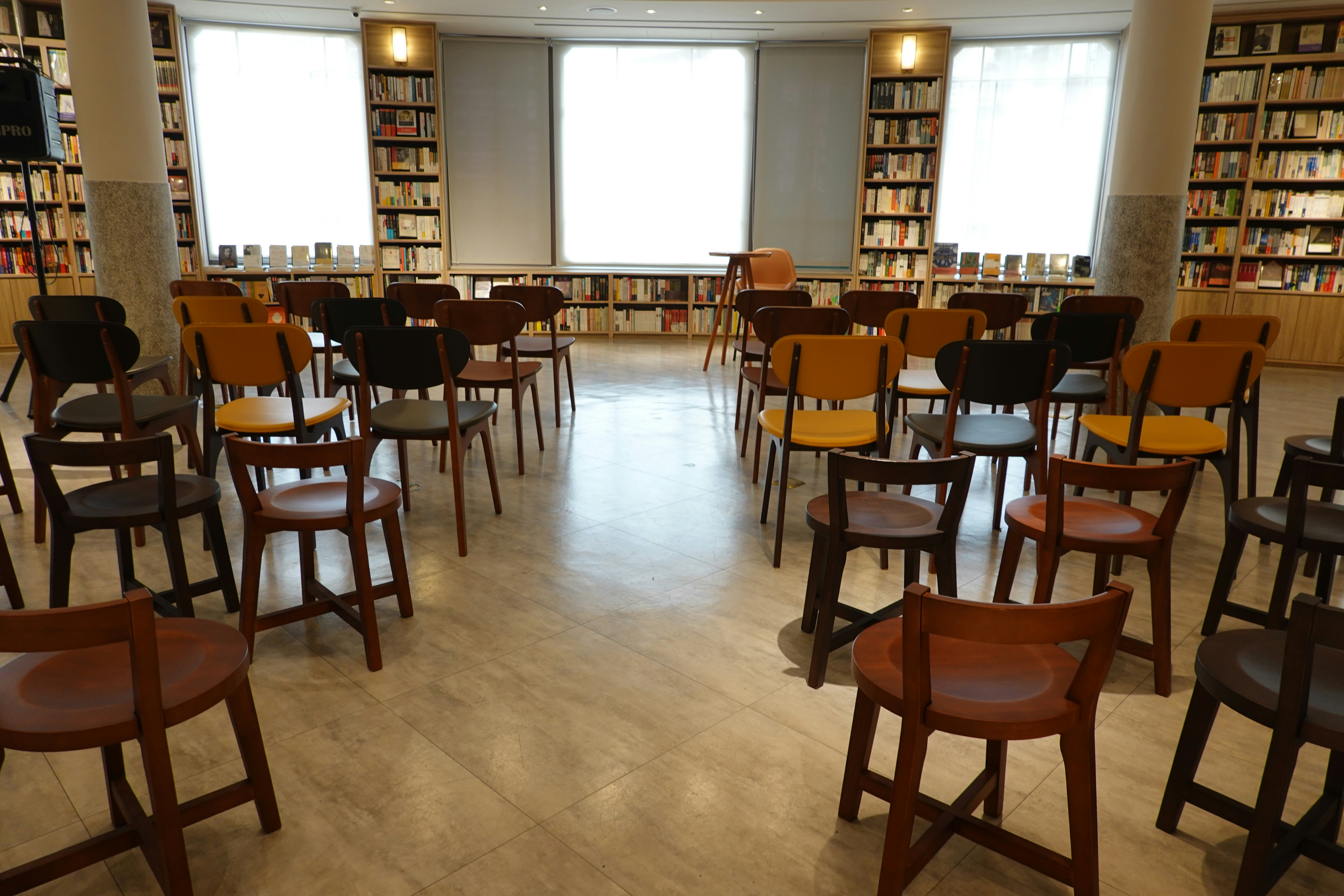 Empty chairs arranged in rows before a central meeting table.
