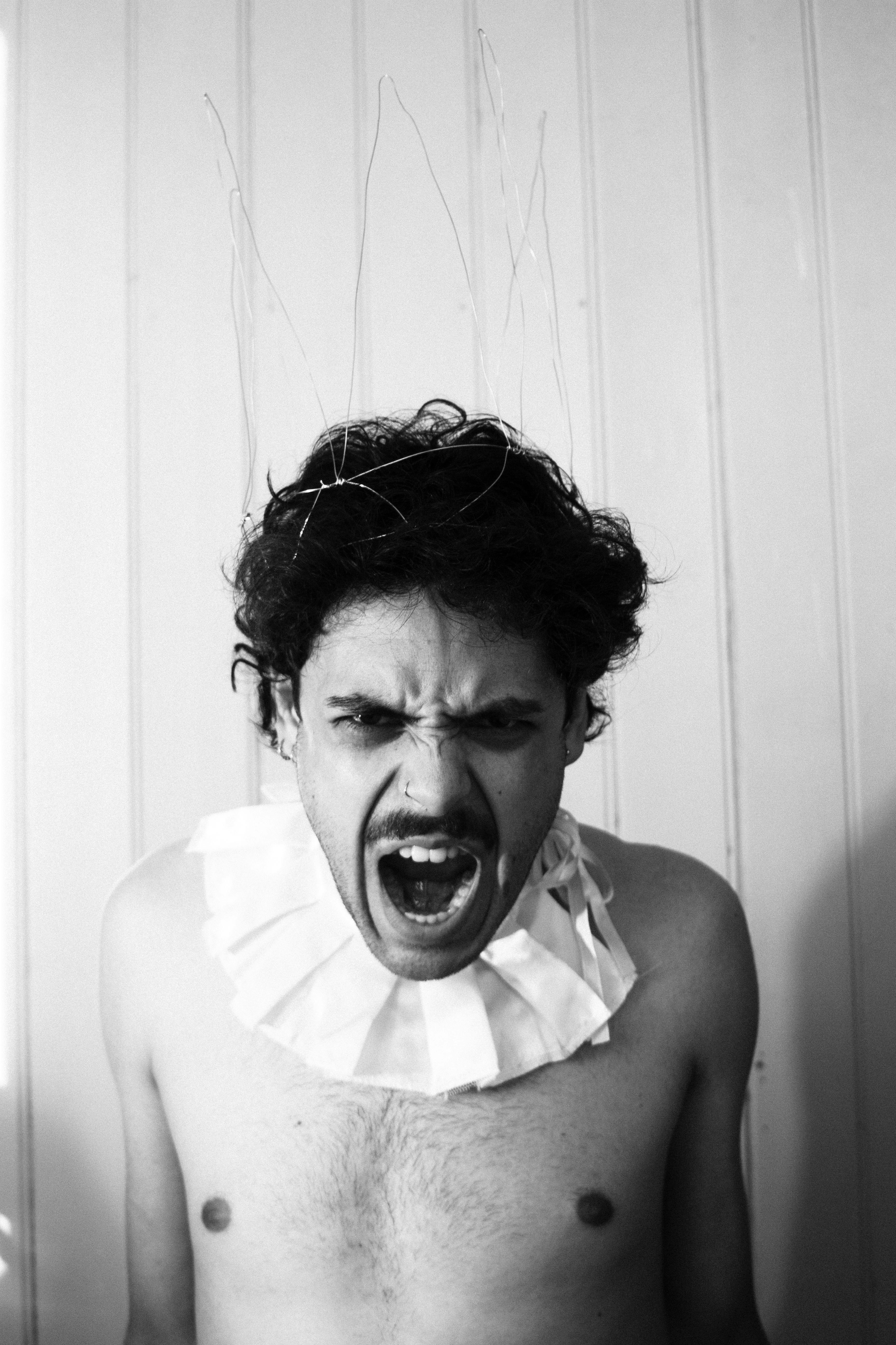 A shirtless man with a ruffle around his neck