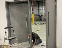 A man kneeling down next to a metal door