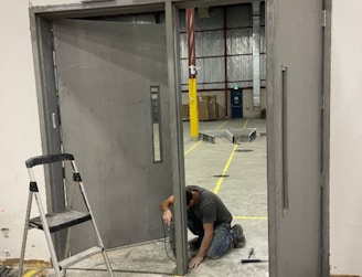 A man kneeling down next to a metal door