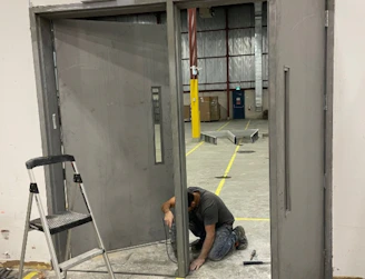 A man kneeling down next to a metal door