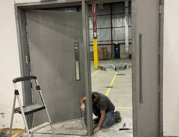 A man kneeling down next to a metal door