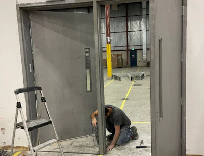 A man kneeling down next to a metal door