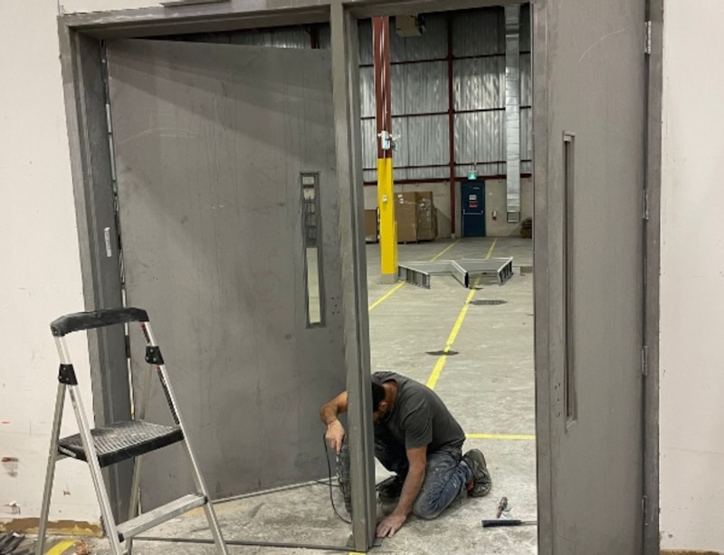 Building maintenance professional inspecting a fire door for defects in a commercial corridor